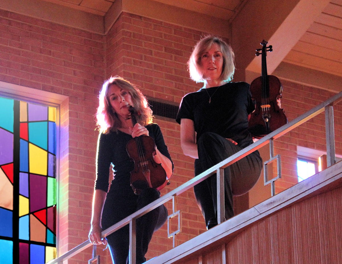 Margie Heath and Jill Farmer from Jolie Deux Violin Duo stand 